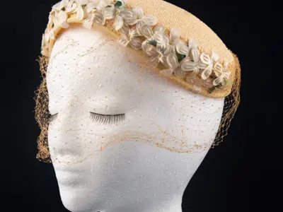 Hazel Davidson: Peach coloured wicker curvette with two rows of white flowers and gold veil.