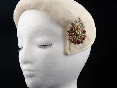 Hazel Davidson: White faux fur curvette or half hat with a bead and embroidery brooch. This style fit snugly over the head almost like a hairband. 