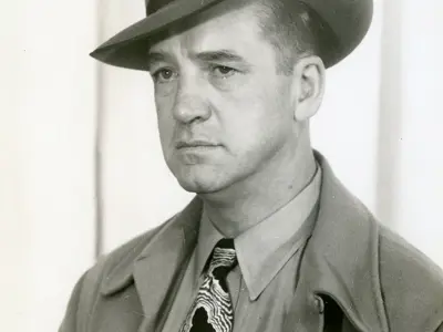 Portrait of Lew Gleeson wearing a fedora.