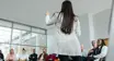 Female speaker leading a motivational seminar with a diverse group of attendees in a modern conference room.